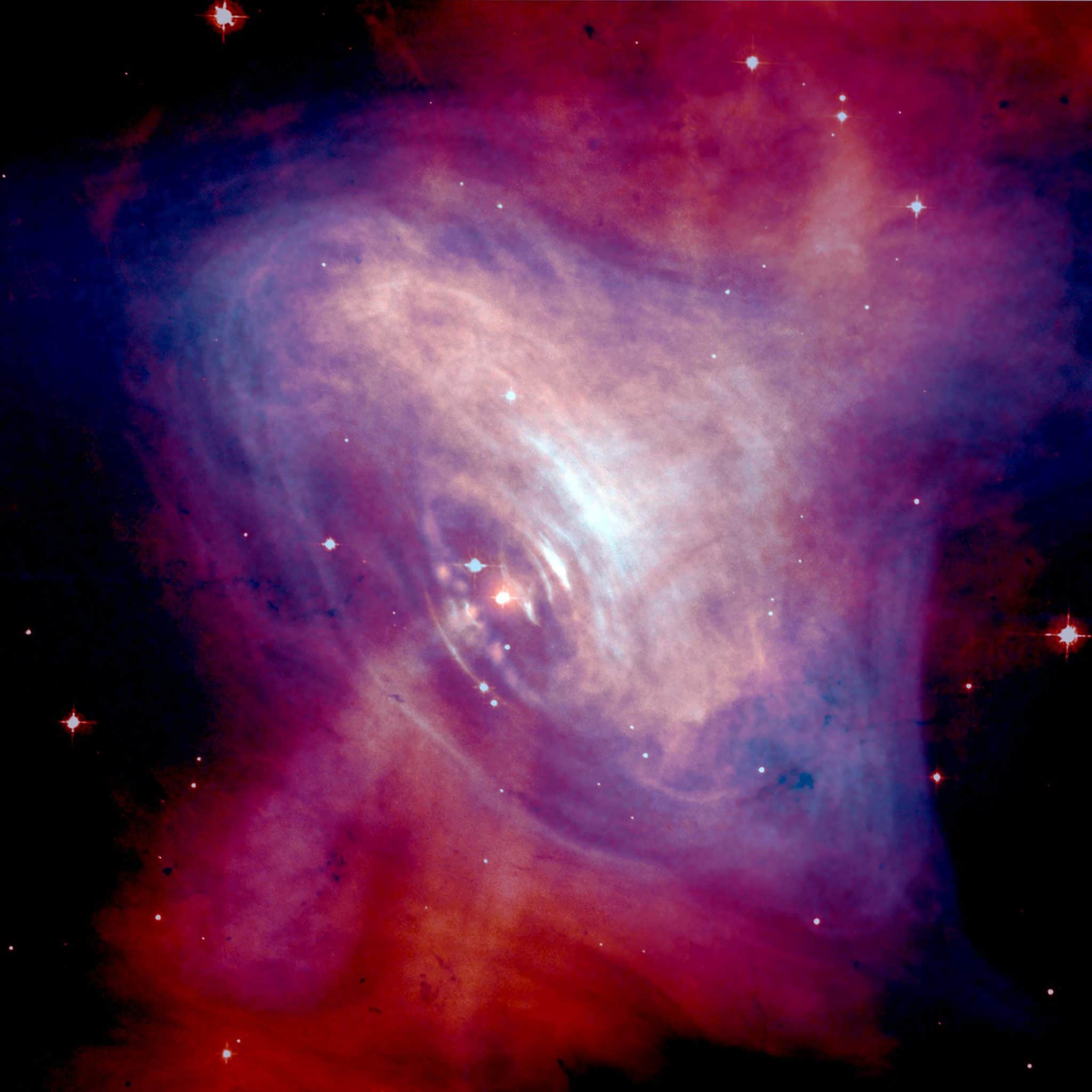 Изображение Крабовидной туманности в условных цветах (синий - рентгеновский, красный - оптический диапазон). В центре туманности - пульсар. НАСА, 2002 г. (Общественное достояние).